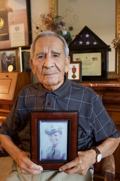 Robert Sanchez holds a photo of himself when he first enlisted in the United States military. Sanchez, then 21 years old, celebrated his 99th birthday in June. (Taylor Jackson Buchanan/Community Impact Newspaper)