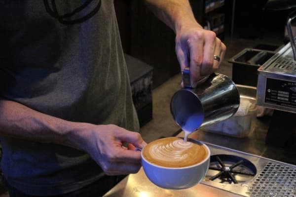 Jeremiah Gray, a manager at The Perc, creates latte art. (Photo by Anna Herod/Community Impact Newspaper)
