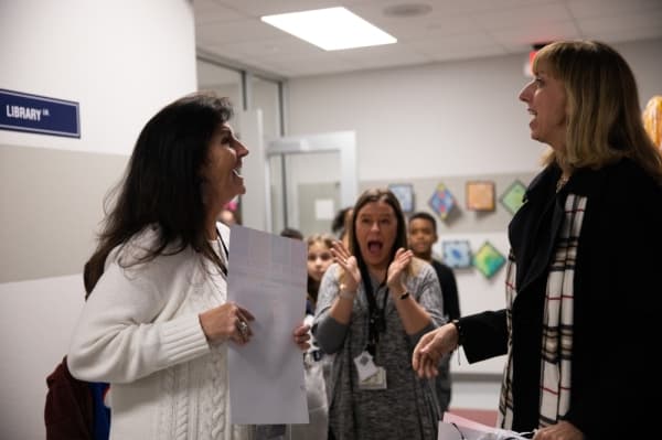 Dallas Gutierrez is caught off guard by the Grant Patrol as she leads her fourth-grade students down the hallway of Meadows Elementary. Her grant will pay for museum instructors from the Perot Museum to visit fourth-grade students in their classes.