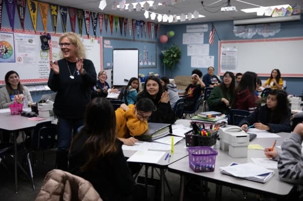 AVID teacher Kristin Haney reacts as the Grant Patrol enters her classroom. Her grant will allow for Armstrong Middle School to take a schoolwide college campus visit.