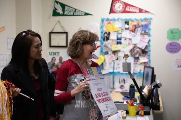 Armstrong Middle School teacher Mary James shows her grant award to her classroom. The grant was awarded to James by Cherie Lo, senior manager of corporate communications at Huawei, one of the Grant Patrol's sponsors. James' grant will go toward the school's Social-Emotional Support Site Team and will provide tools for calming and restorative teaching practices.