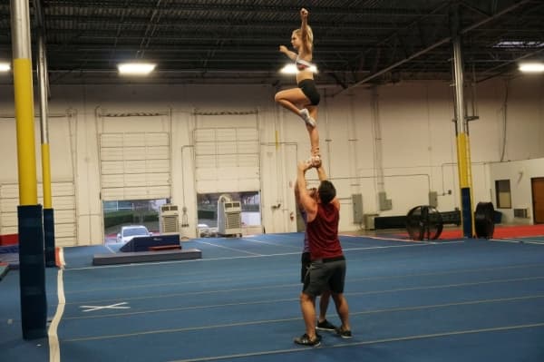 Sullivan and a coworker practice a cheer maneuver with a Spirit of Texas athlete. (Gavin Pugh/Community Impact Newspaper)