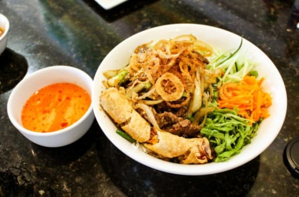 Vermicelli ($10.49) is a thin rice noodle, served here with a shredded lettuce, cucumber, carrots, fried onions, an egg roll, a choice of protein and fish sauce. (Andy Li, Community Impact Newspaper)