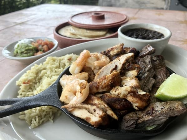 The Asada El Mon includes marinated and grilled fajitas with rajas and a side of crema, guacamole, pico de gallo, rice and beans. (Sally Grace Holtgrieve/Community Impact Newspaper)