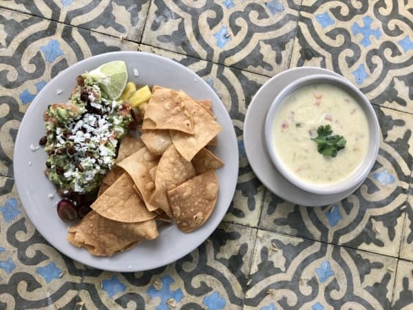 The guacamole (left) consists of hand-mashed avocados with pico de gallo, seasonal fruit, cotija and pepitas, and the Queso El Mon is a blend of American cheese with Hatch green chiles, onions, tomatoes and cilantro.  (Sally Grace Holtgrieve/Community Impact Newspaper)