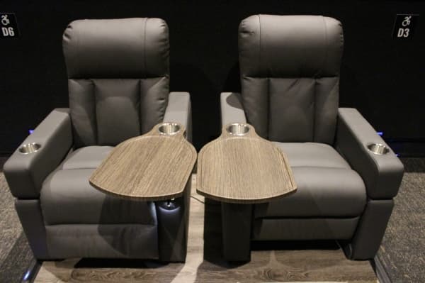 Guests are seated in  leather reclining seats with trays for food and drink. Photo by Andrew Christman/Community Impact Newspaper