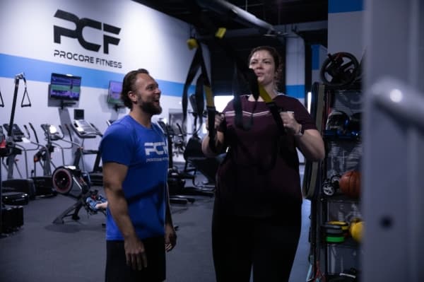 Trainer Tony West encourages Lindy Langston through a series of TRX rows during their one-on-one training session. (Liesbeth Powers/Community Impact Newspaper)