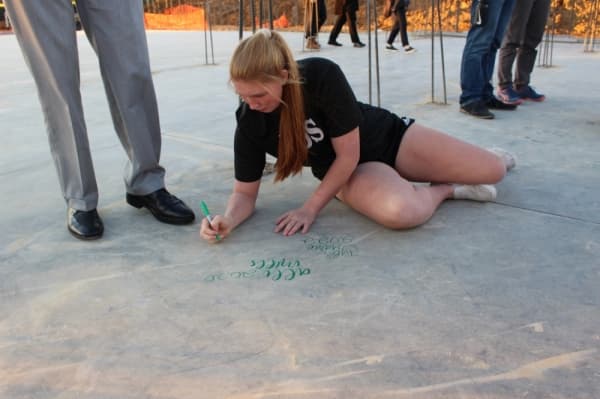Carroll ISD students and supporters sign the slab of the upcoming new music center Dec. 11. (Miranda Jaimes/Community Impact Newspaper)