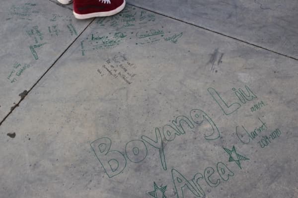 The foundation slab of the new Carroll ISD music center was signed by the community in green marker. (Miranda Jaimes/Community Impact Newspaper)