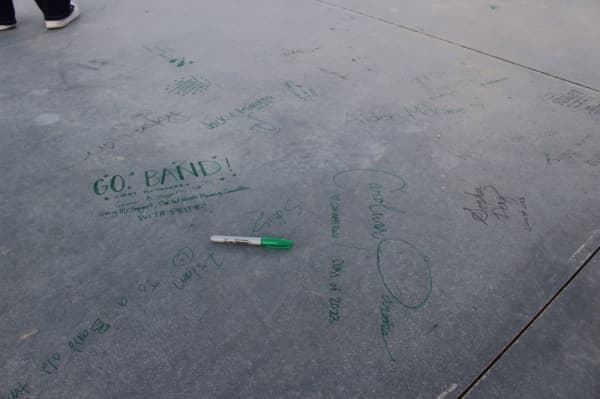 The foundation slab of the new Carroll ISD music center was signed by the community in green marker. (Miranda Jaimes/Community Impact Newspaper)