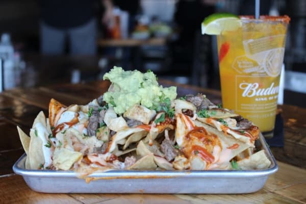 The Kitchen Sink Nachos ($12.99): Fajita chicken, fajita beef with chili, homemade green chile queso, Sriracha sour cream, avocado cream and Scoundrel Sauce topped with guacamole (Nola Z. Valente/Community Impact Newspaper)