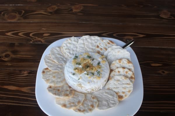 Patio Dolcetto's baked brie is served with water crackers and topped with a choice of pepper bacon jam, pecans and Texas honey, or garlic, thyme and truffle oil. (Evelin Garcia/Community Impact Newspaper)