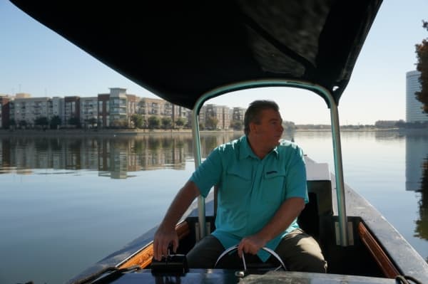General Manager Kevan Burt steers one of the electric-powered boats through Lake Carolyn. (Gavin Pugh/Community Impact Newspaper)