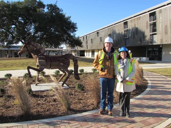 Menchace Principal Eliza Loyola and Drew Johnson, AISD's director of bond planning and controls, stand next to a Menchaca Mustang statue at the new campus Dec. 17. (Nicholas Cicale/Community Impact Newspaper)