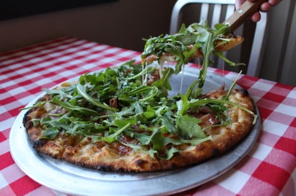The Pig & Fig pizza from Brick & Brews is made with a four-cheese blend, fig jam spread and shaved prosciutto, and topped with organic baby arugula and drizzled with olive oil, Texas honey and lemon dressing. (Kara McIntyre/Community Impact Newspaper)