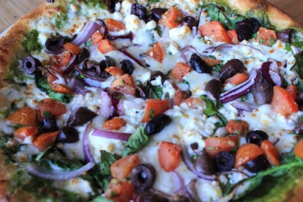 Zilker Love pizza: $10.95. This pesto-based vegetarian pizza comes with fontina, mozzarella, feta cheese, spinach, red onions, marinated tomatoes and Kalamata olives. Jack Flagler/Community Impact Newspaper