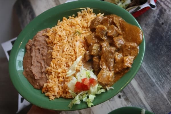 Carne guisada ($3.25 taco, $9.25 plate): Beef tips with gravy are served on a taco or on a plate with a side of refried beans and rice. (Danica Smithwick/Community Impact Newspaper)