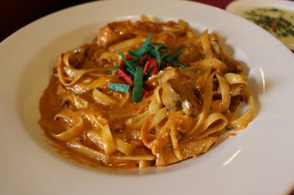 The spicy chicken Alfredo ($11.95) includes creamy Alfredo with bacon, mushrooms, shallots and tomato, served with a house salad. The dinner portion of this dish is $15.95. (Kara McIntyre/Community Impact Newspaper)