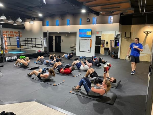 A photo of a fitness class doing core exercises on the floor.