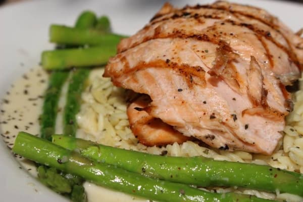 The crab and artichoke stuffed salmon ($18.50) features grilled Atlantic salmon, artichoke hearts, fresh spinach, crab and spinach. It is served with orzo pasta and asparagus, dressed in a lemon basil butter. (Renee Yan/Community Impact Newspaper)