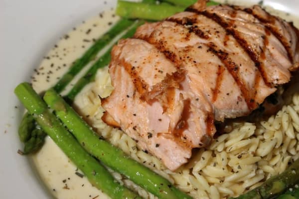 The crab and artichoke stuffed salmon ($18.50) features grilled Atlantic salmon, artichoke hearts, fresh spinach, crab and spinach. It is served with orzo pasta and asparagus, dressed in a lemon basil butter. (Renee Yan/Community Impact Newspaper)