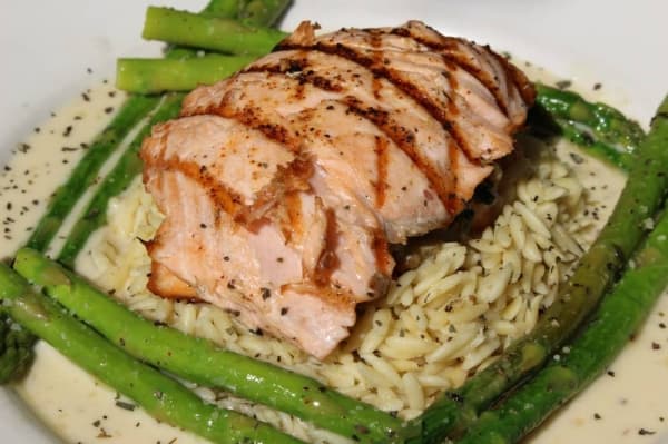 The crab and artichoke stuffed salmon ($18.50) features grilled Atlantic salmon, artichoke hearts, fresh spinach, crab and spinach. It is served with orzo pasta and asparagus, dressed in a lemon basil butter. (Renee Yan/Community Impact Newspaper)