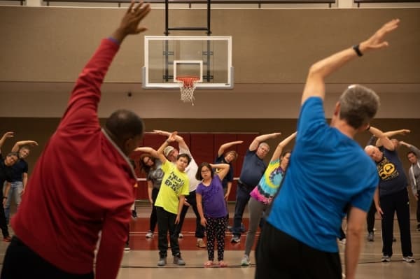 Yoga instructor Roberts Speaks leads visitors in stretches and warmups alongside Mayor Harry LaRosiliere before teaching a free yoga class. (Liesbeth Powers/Community Impact Newspaper)