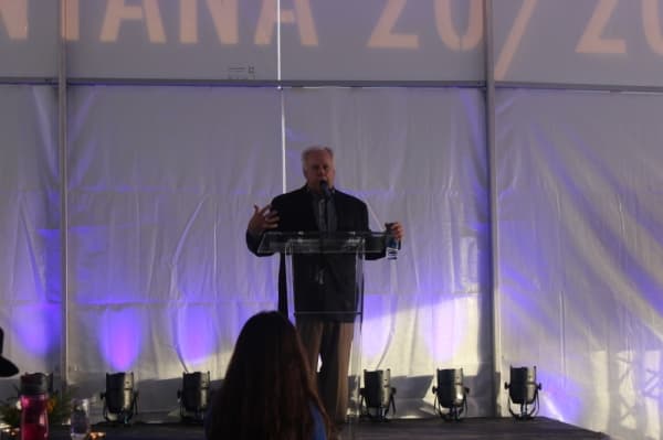 A photo of a man speaking at a podium.