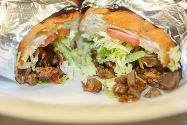 The torta de asada is served with beans, lettuce, tomatoes, mayonnaise and red salsa. (Evelin Garcia/Community Impact Newspaper)