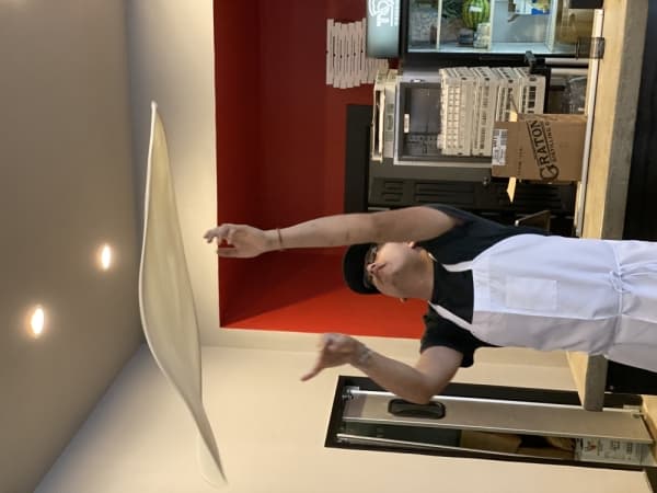 Toss Pizzeria Kitchen Manager Trinidad Ramirez twirls a large, 20-inch dough into the air.