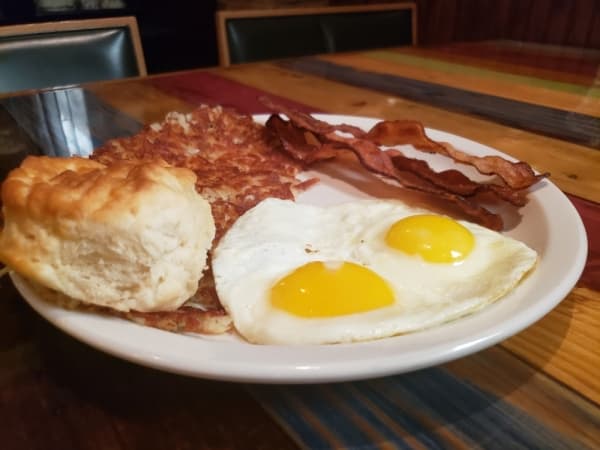 Two egg breakfast with eggs sunny side up, bacon, hash browns and a biscuit ($7.59)
