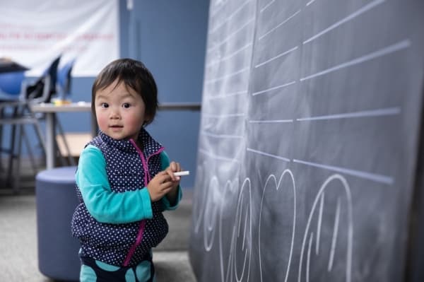 Angela pauses before adding her scribbles to the "We are Plano ISD Proud..." chalk board at the 2020 diversity celebration. (Liesbeth Powers/Community Impact Newspaper)