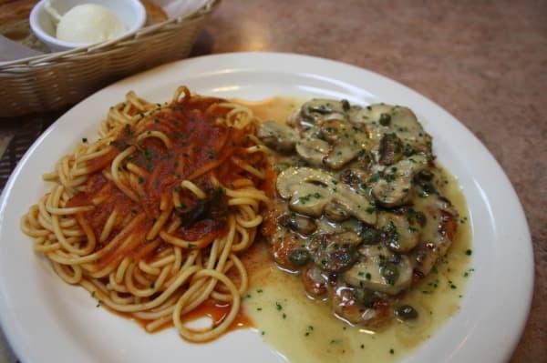 Chicken piccata is made with sauteed chicken breast, served in lemon butter sauce with mushrooms, capers and spaghetti pomodoro. (Shawn Arrajj/Community Impact Newspaper)