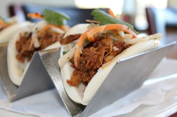 The Bao Mi Tacos ($10.50) appetizer includes steamed bao buns filled with pulled pork, a tikka masala-based barbecue sauce and a coleslaw with Central American influences. (Renee Yan/Community Impact Newspaper)