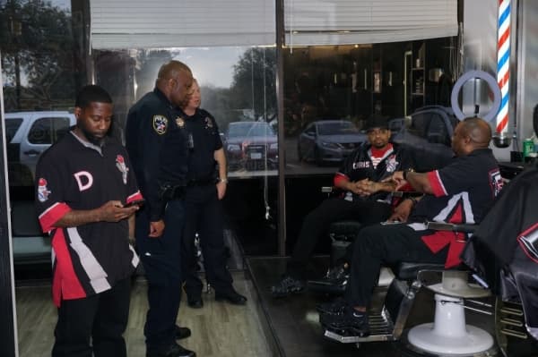 Irving Police Officer Jonathan Plunkett (second from left) talks with barbers at Demetrius Ennett’s (left) 5 Star Cutz. (Gavin Pugh/Community Impact Newspaper)