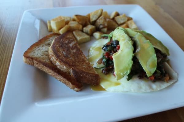 Huevos rancheros ($12.50) includes two over-medium eggs with cheese, mushrooms, peppers, onions, bacon, avocado, spinach and honey mustard.