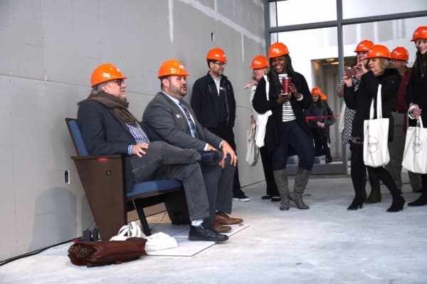 Hargis and a tour-goer test the theater seats that will be installed in the main hall. (Gavin Pugh/Community Impact Newspaper)
