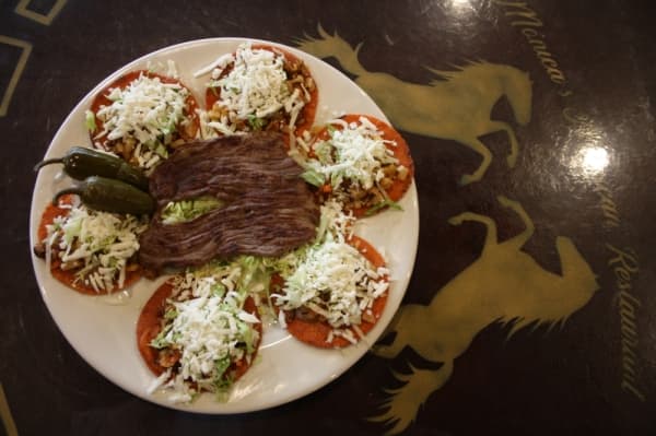 Enchilada Lagunillas include six mini corn tortillas topped with refried beans and a mix of potatoes, carrots, chorizo, lettuce, cheese and choise of chicken, cecina, beef or quail. (Shawn Arrajj/Community Impact Newspaper)