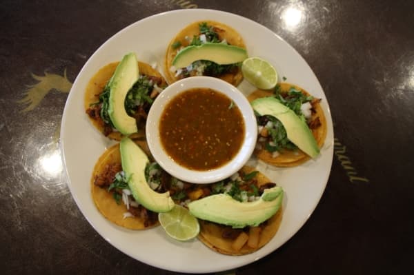 Mexican Taquitos include five al pastor pork taquitos, topped with cilantro, onion and sliced avocado. (Shawn Arrajj/Community Impact Newspaper)