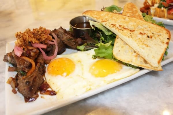 Vietnamese Steak & Eggs ($14.99) is made with locally sources, marinated, center-cut top sirloin and served with two eggs, a side salad and La Baccia toast. 