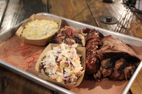 The three-meat plate ($21) delivers about a pound of meat total. Here it is complemented by creamed corn with roasted green chile and coleslaw. 