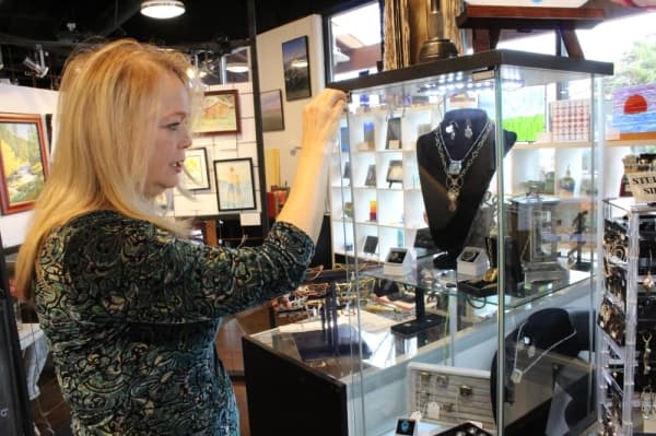 Anita Robbins shows handcrafted jewelry made by Studio Art House artists. (Anna Herod/Community Impact Newspaper)