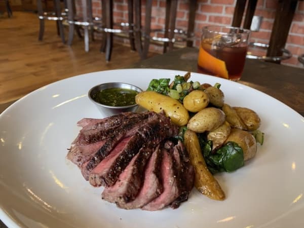 The wood-grilled Wagyu sirloin steak ($23-$36) is served with roasted potatoes, Swiss chard and chimichurri.(Renee Yan/Community Impact Newspaper)