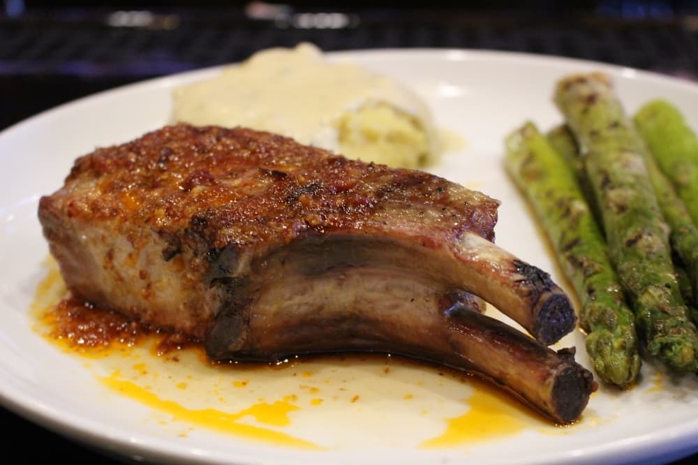 The 14-ounce, double bone-in pork chop is prepared in a sweet and spicy barbecue bacon glaze and served with a choice of two signature side offerings ($19). (Ben Thompson/Community Impact Newspaper)