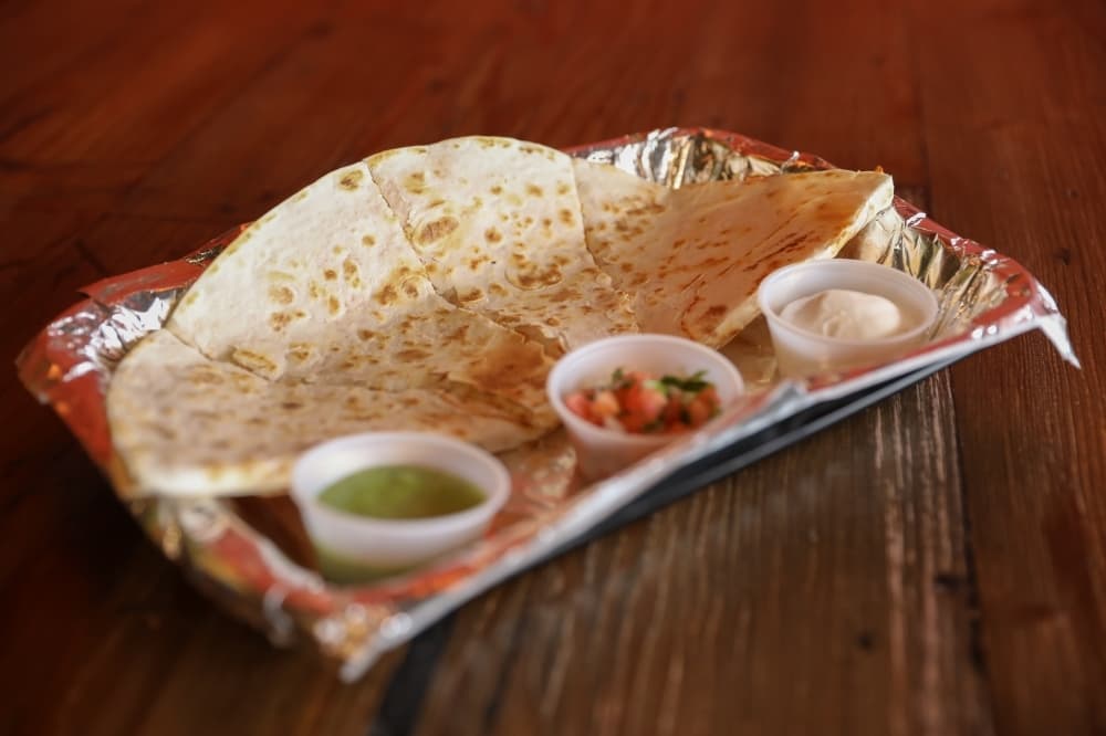 Tommy Tamale quesadillas ($8 for one 12-inch, $12 for two) can be made with steak, tamale pork, chicken or beans and are served with sour cream, salsa and pico de gallo. (Photos by Liesbeth Powers/Community Impact Newspaper)