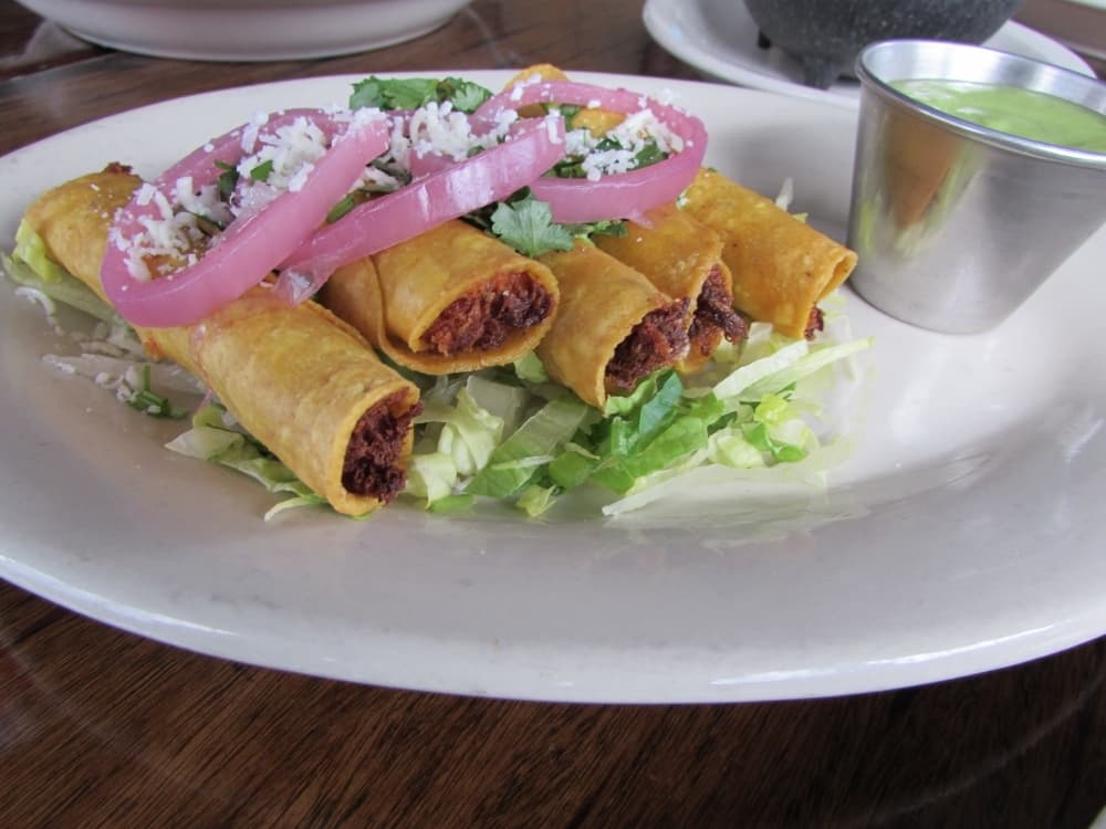 Flautitas De Pollo are topped with pickled red onions and cheese. (Nicholas Cicale/Community Impact Newspaper)