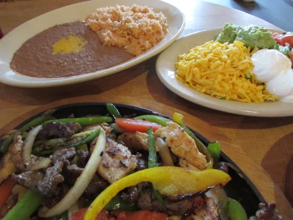 Fajitas at Maudie’s can be ordered with chicken and/or beef and come with a plate or rice and beans as well as sour cream, cheese and vegetables.  (Nicholas Cicale/Community Impact Newspaper)