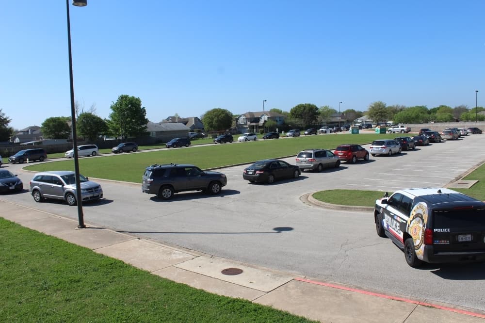 Vehicles waiting to get free breakfast and lunch bags for Leander ISD students March 25 snake through the parking lot at Bagdad Elementary School in Leander. (Brian Perdue/Community Impact Newspaper)