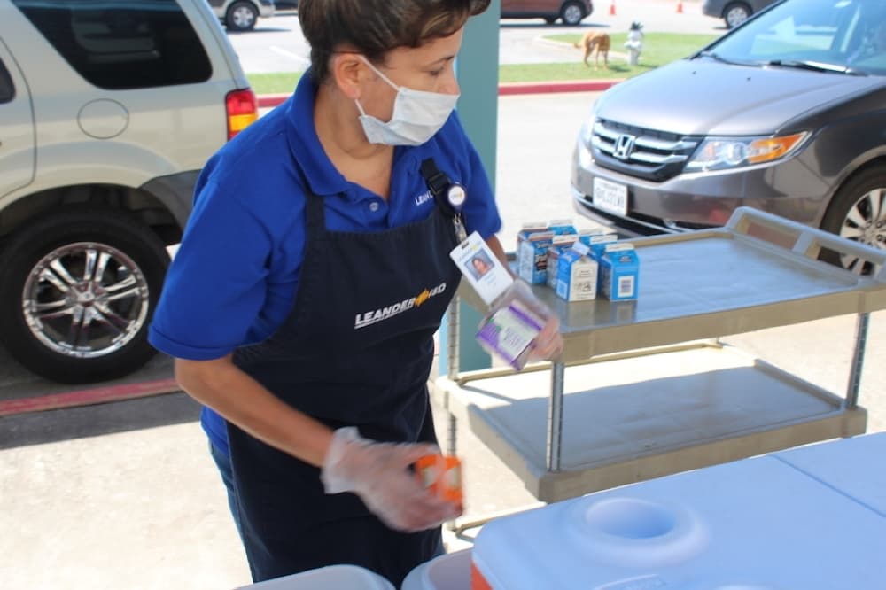 A Leander ISD Child Nutrition Services employee rushes to add juice to free meal bags March 25 at Bagdad Elementary School in Leander. (Brian Perdue/Community Impact Newspaper)