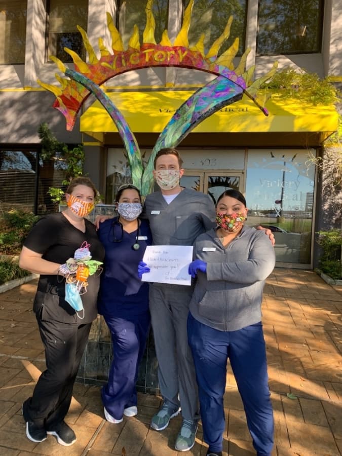 A photo of four medical workers wearing hand-sewn masks and holding a sign that reads "Thank you #MakeAMask sewers."